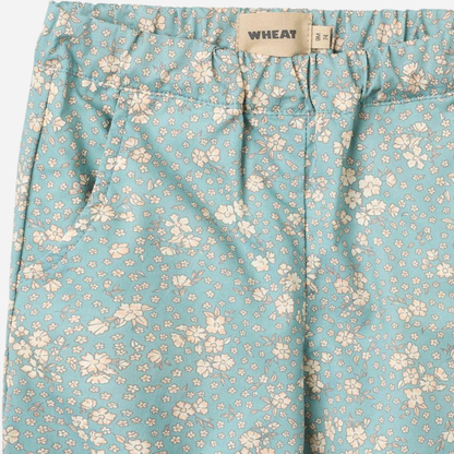 Sold at Bombon Shop, designed by Wheat, spring lake flowers organic cotton baby trousers in soft blue floral print with elastic waist and relaxed fit.