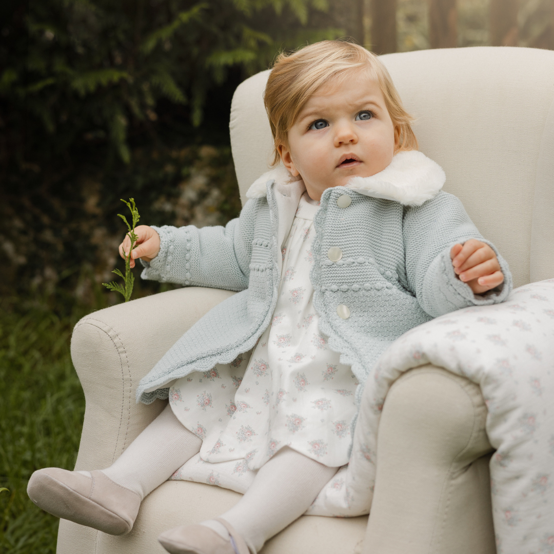 Sold at Bombon shop, designed by Paz Rodriguez, ivory baby dress with pink floral print, scalloped hem, pink bow detail, and matching bloomers.