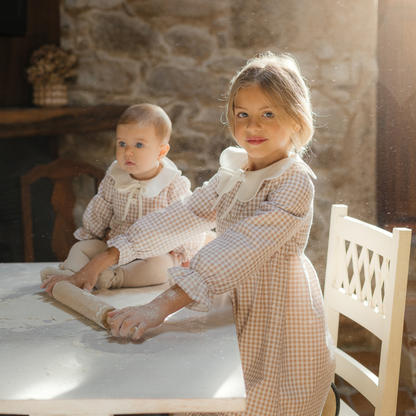 Sold at Bombon shop, designed by Paz Rodriguez, beige gingham baby romper with white collar and long sleeves.