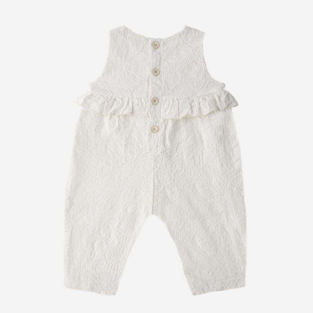 Sold at Bombon Shop, designed by 1+ in the family, off-white baby overall with textured cotton fabric and delicate ruffle detail across the chest.
