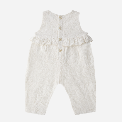 Sold at Bombon Shop, designed by 1+ in the family, off-white baby overall with textured cotton fabric and delicate ruffle detail across the chest.