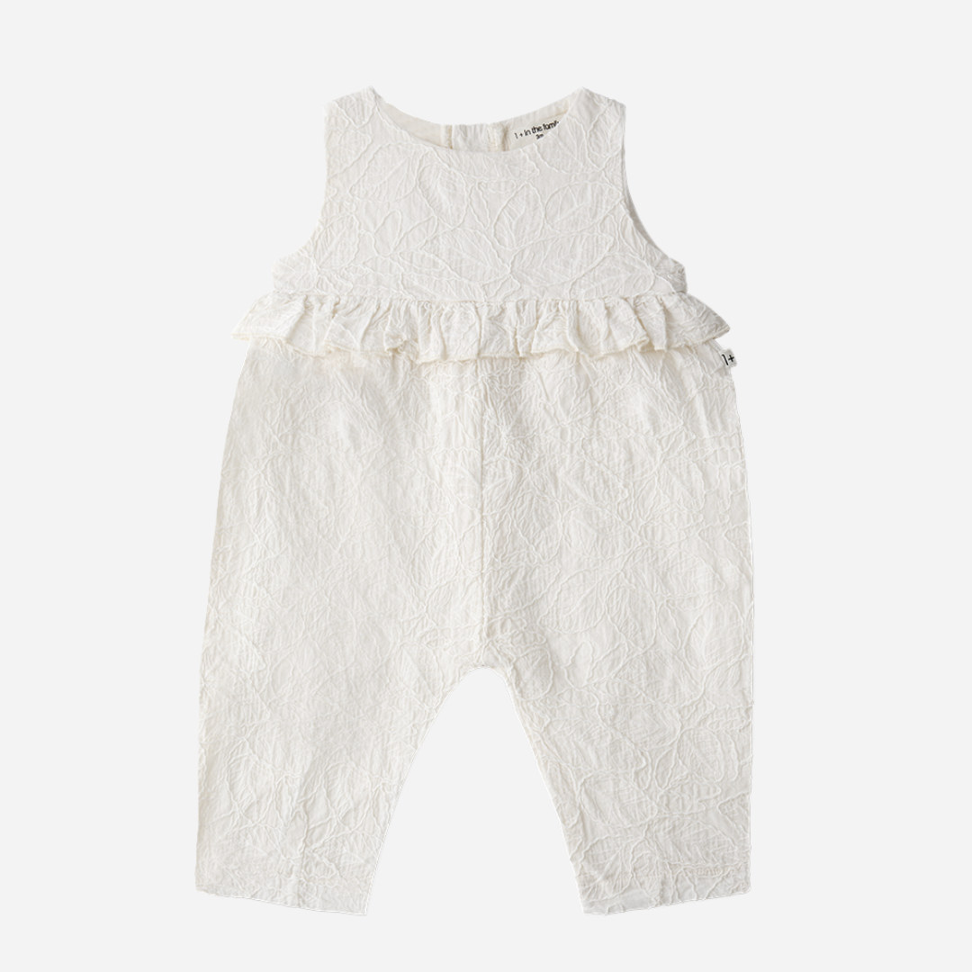 Sold at Bombon Shop, designed by 1+ in the family, off-white baby overall with textured cotton fabric and delicate ruffle detail across the chest.