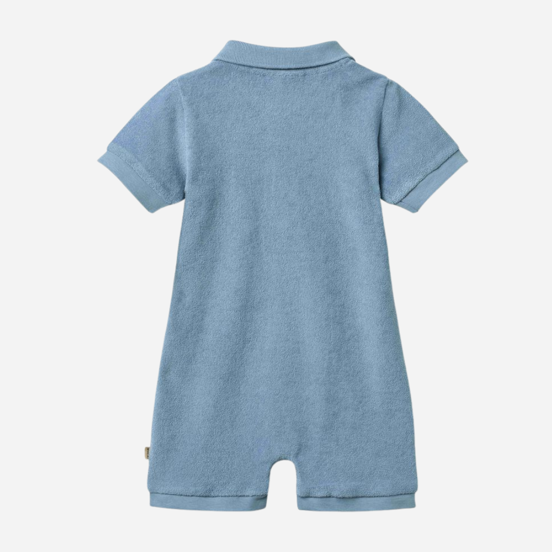 Sold at Bombon Shop, designed by Wheat, faded denim organic cotton short sleeve playsuit with polo collar and soft washed blue tone.
