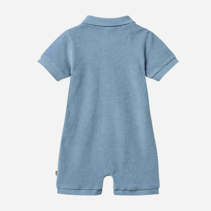 Sold at Bombon Shop, designed by Wheat, faded denim organic cotton short sleeve playsuit with polo collar and soft washed blue tone.