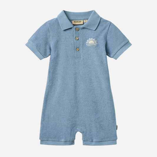 Sold at Bombon Shop, designed by Wheat, faded denim organic cotton short sleeve playsuit with polo collar and soft washed blue tone.