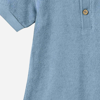 Sold at Bombon Shop, designed by Wheat, faded denim organic cotton short sleeve playsuit with polo collar and soft washed blue tone.