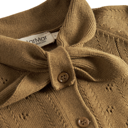 Sold at Bombon shop, designed by MarMar Copenhagen — golden brown cotton knit baby cardigan with bow tie collar and pointelle details, pairs perfectly with the floral skirt.