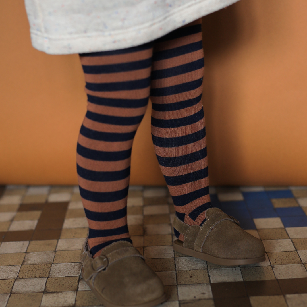 Sold at Bombon shop, designed by 1+ in the family — striped castagna and navy knit baby tights with feet.