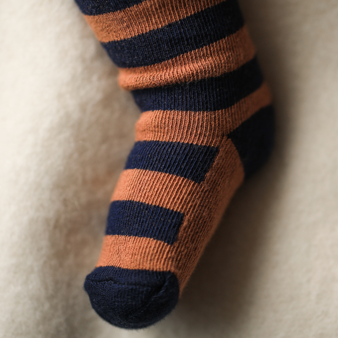 Sold at Bombon shop, designed by 1+ in the family — striped castagna and navy knit baby tights with feet.
