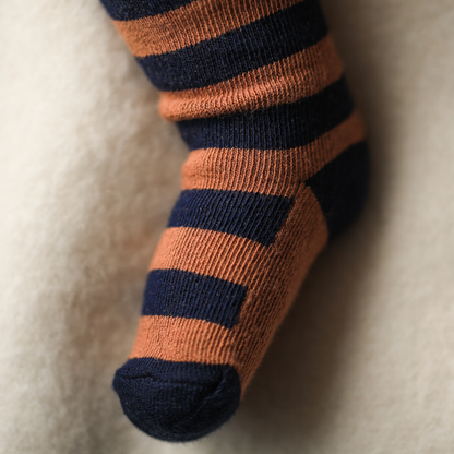Sold at Bombon shop, designed by 1+ in the family — striped castagna and navy knit baby tights with feet.