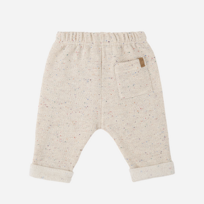 Sold at Bombon shop, designed by 1+ in the family — oatmeal-colored baby pants with multicolor speckles, contrast drawstring, and rolled cuffs, photographed flat on white background. back