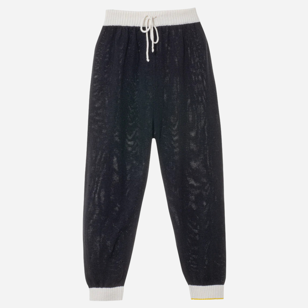 Sold at Bombon and designed by Gensami, navy blue knit baby pants with a white drawstring waistband, ribbed cuffs, and a yellow trim detail at the ankle.