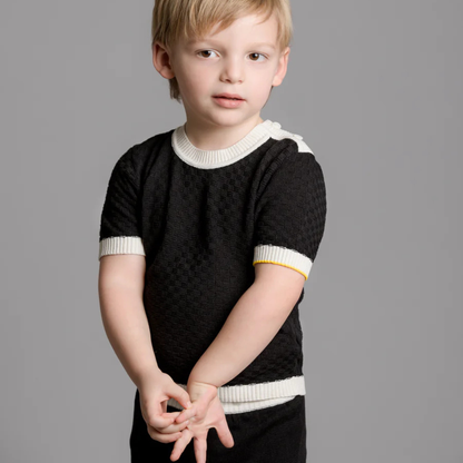 Sold at Bombon and designed by Gensami, navy blue knit baby pants with a white drawstring waistband, ribbed cuffs, and a yellow trim detail at the ankle.