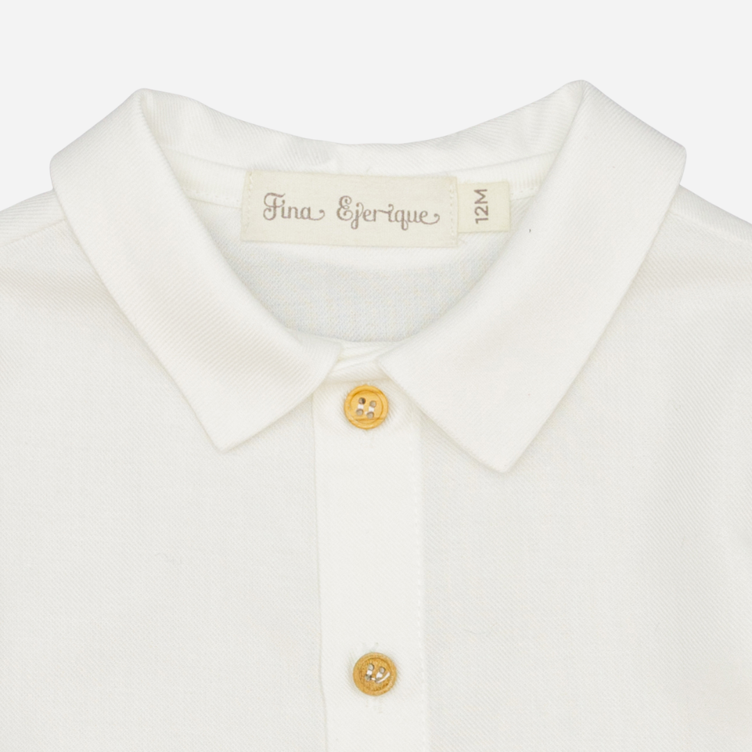 Sold at Bombon shop, designed by Fina Ejerique, a white viyella baby shirt with rounded collar, wooden buttons, and long sleeves. zoom