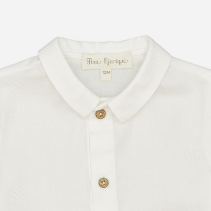 Sold at Bombon shop, designed by Fina Ejerique, a white viyella baby shirt with rounded collar, wooden buttons, and long sleeves. zoom