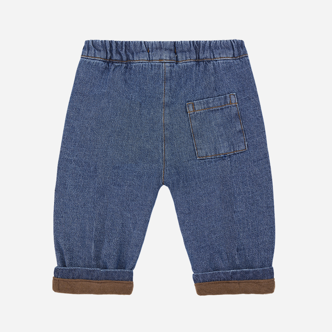 Sold at Bombon shop, designed by 1+ in the family – William baby pants in soft denim with front pockets, elastic waistband, and brown fleece-lined cuffs. back