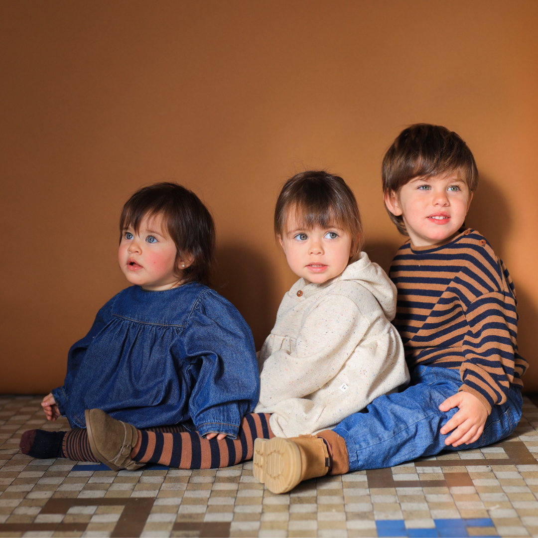 Sold at Bombon shop, designed by 1+ in the family – William baby pants in soft denim with front pockets, elastic waistband, and brown fleece-lined cuffs. model