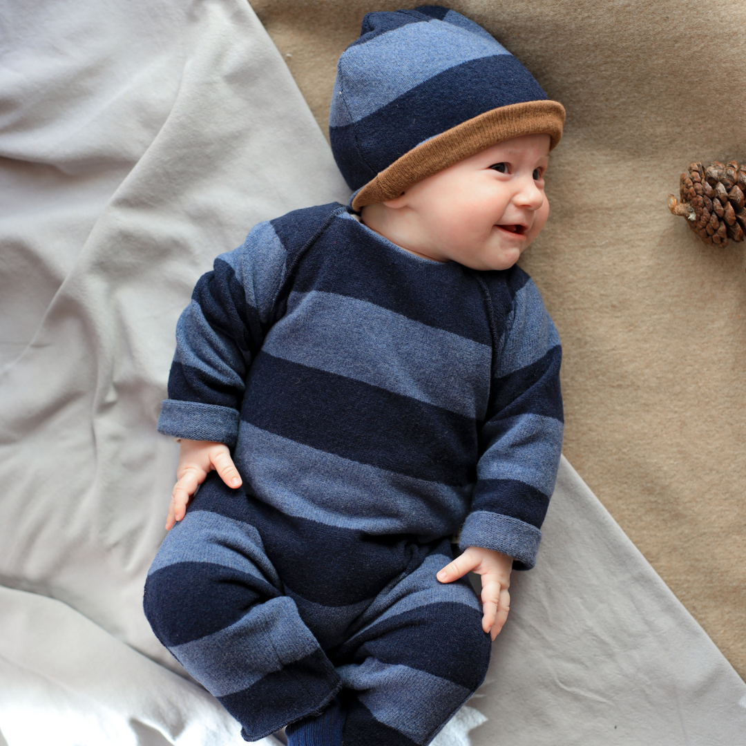 Sold at Bombon shop, designed by 1+ in the family – navy and grey striped baby jumpsuit with long sleeves and soft fabric, shown flat on white background model