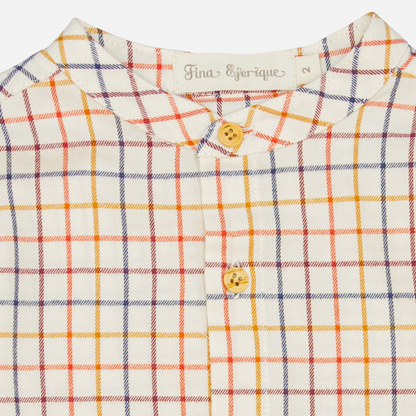 Sold at Bombon shop, designed by Fina Ejerique, a beige viyella baby shirt with red, mustard, and blue checkered pattern, wooden buttons, and long sleeves. zoom