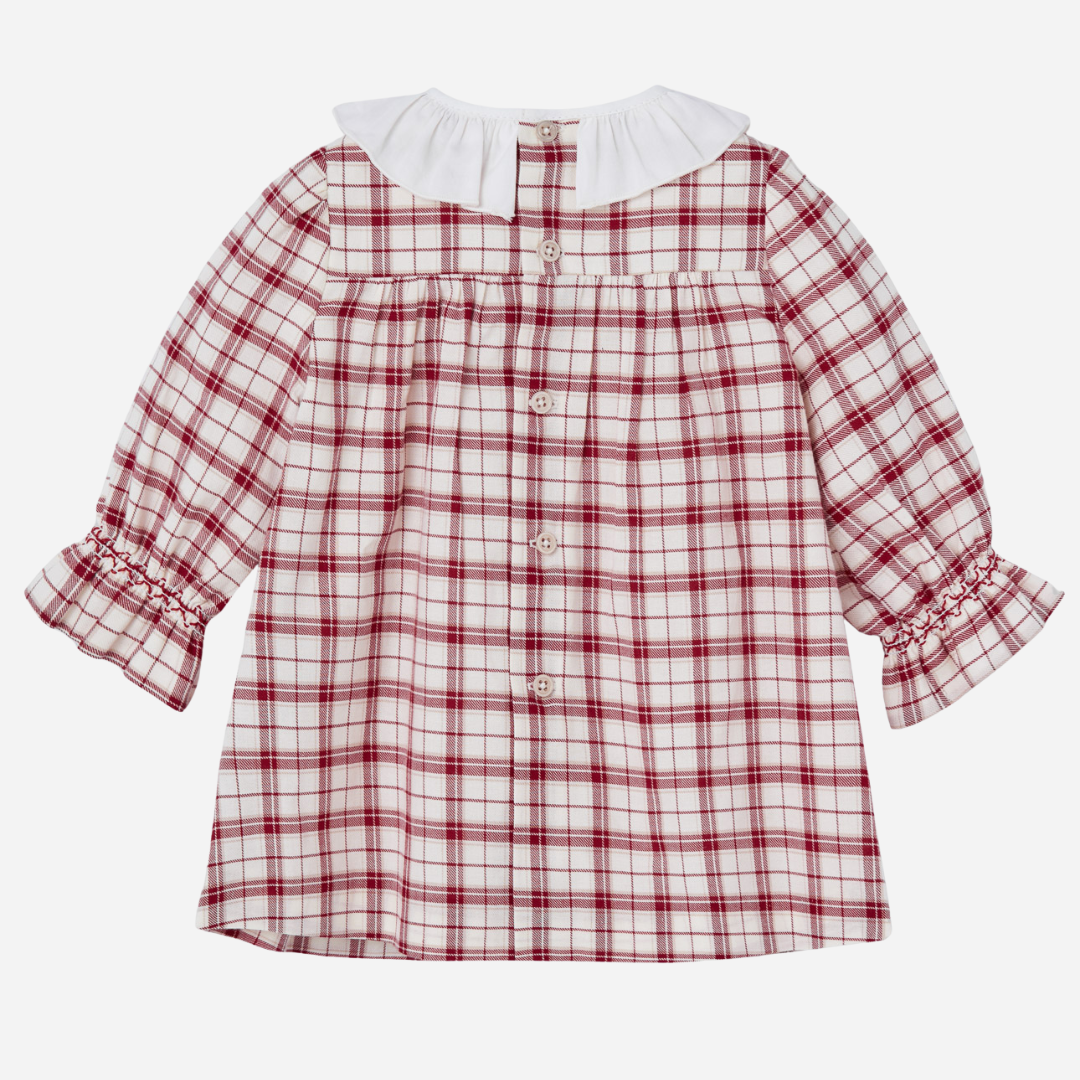 Sold at Bombon shop, designed by Paz Rodriguez, baby holiday dress in red plaid with smocking, white ruffle collar, and velvet bow.