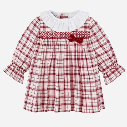Sold at Bombon shop, designed by Paz Rodriguez, baby holiday dress in red plaid with smocking, white ruffle collar, and velvet bow.