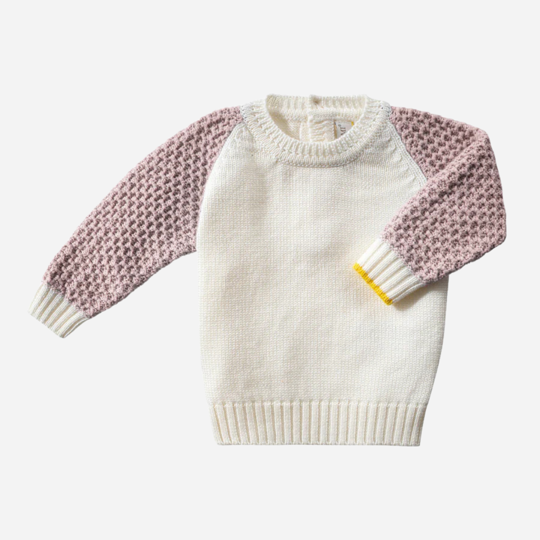 Sold at Bombon and designed by Gensami, a baby knit set featuring an ivory sweater with pink textured sleeves and matching ivory pants, detailed with yellow trim accents.