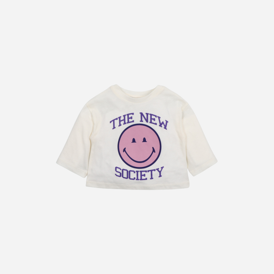 Sold at Bombon shop, this baby girl sweatshirt by The New Society features a cream base with a bold pink smiley face graphic and purple “The New Society” lettering, combining cozy comfort with playful, modern style. front