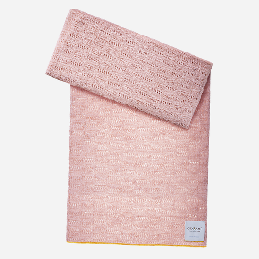 Sold at Bombon and designed by Gensami, a pink knitted baby blanket with openwork texture and a contrasting yellow trim along the border.